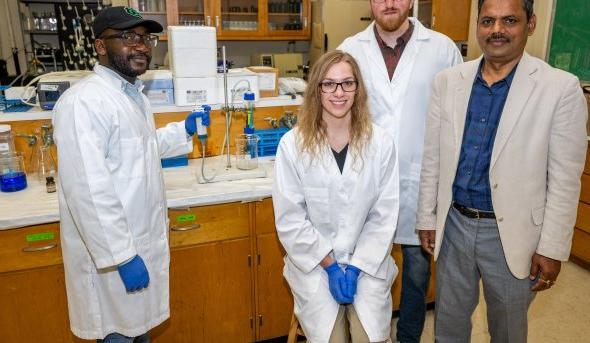 Four people stand together in a laboratory 